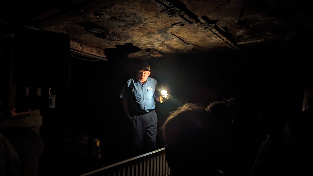 a retired coal miner leading a tour group in an old coal mine featured in a guide to beckley, wv